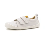 Zapatilla infantil blanca con dos tiras de velcro, puntera de malla, suela blanca y etiqueta mostaza en la lengüeta