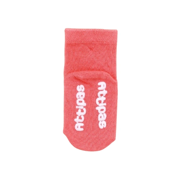 Calcetín infantil Attipas de color coral con el logotipo antideslizante en blanco sobre la planta