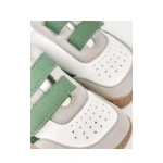 Detalle de unas zapatillas infantiles Lejan blancas con dos velcros verdes, ante gris, puntera perforada y suela caramelo