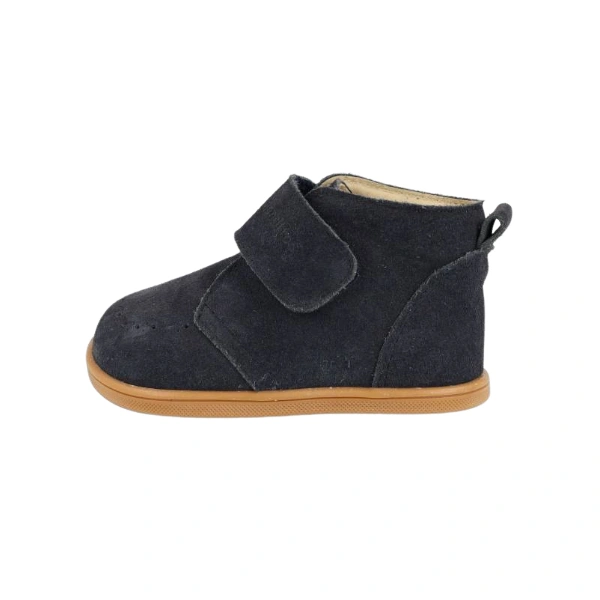 Bota infantil de serraje azul marino con cierre de velcro, tirador trasero y suela color miel, vista de perfil