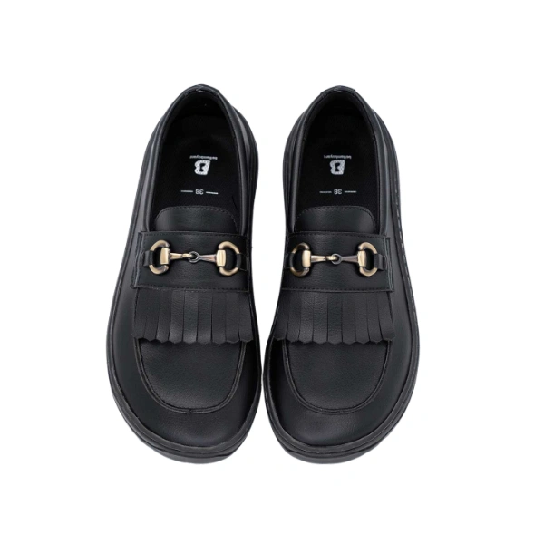 Mocasín Glow negro de Beflamboyant visto desde arriba, con flecos y bocado metálico dorado en el empeine