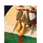 Niño con sandalias barefoot Muris Rio Jr mostaza de dos tiras sentado en la proa de una barca con un flotador