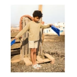Niño con sandalias Muris Rio Jr azul cielo sobre un palé de madera, sujetando unas aletas azules junto al mar