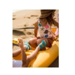 Niña con sombrero de paja sentada en un kayak amarillo en la playa con las sandalias Muris Aruba Mini aguamarina