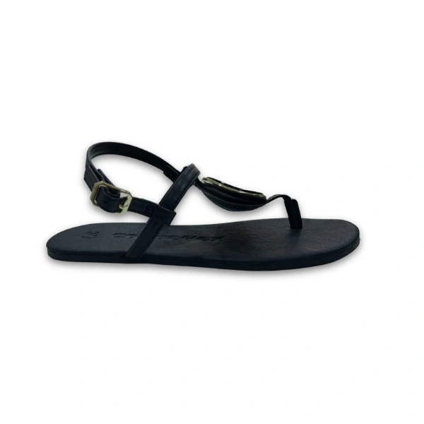 Sandalia Medallion de Coqueflex en negro, vista lateral, con medallón de borde dorado en la tira y hebilla al tobillo